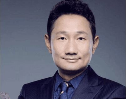 Portrait of a person in a suit and tie against a gray background.